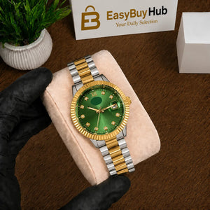 A gold and silver metal watch with a green dial and bezel, displayed on a beige cushion held by a hand wearing a black glove. The background is a brown wooden surface with a small potted plant and a box labeled 'EasyBuyHub'.