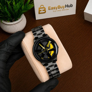 A black wristwatch with a yellow accent dial is displayed on a beige cushion held by a gloved hand over a wooden table. A small potted plant and a card reading EasyBuyHub are visible in the background.