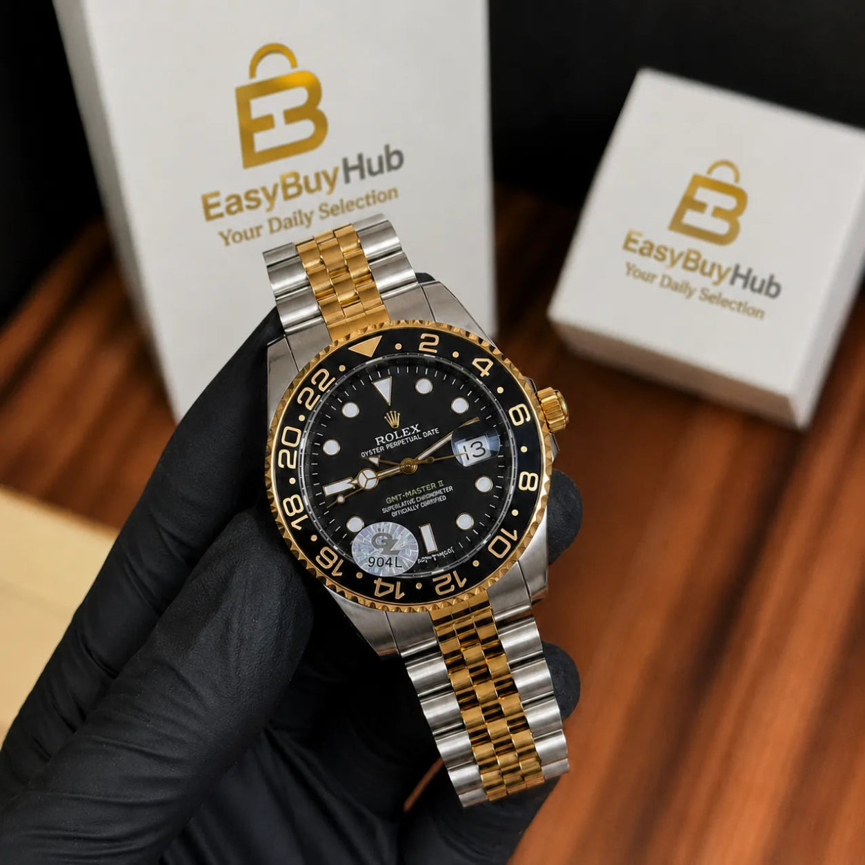 A Rolex Submariner Date watch with a black dial, black bezel, and a two-tone silver and gold stainless steel bracelet, held by a hand wearing a black glove. The background features white boxes branded with 'EasyBuyHub'.