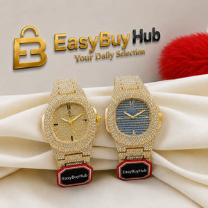 Two gold-tone wristwatches covered in rhinestones, displayed on draped cream fabric. One watch has a gold dial and the other has a blue-and-gold striped dial.