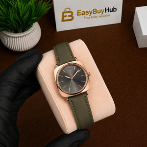 A wristwatch with a dark gray dial and olive green strap, held by a black-gloved hand on a beige display cushion over a brown wooden surface. A branded card reading EasyBuyHub is visible in the background.